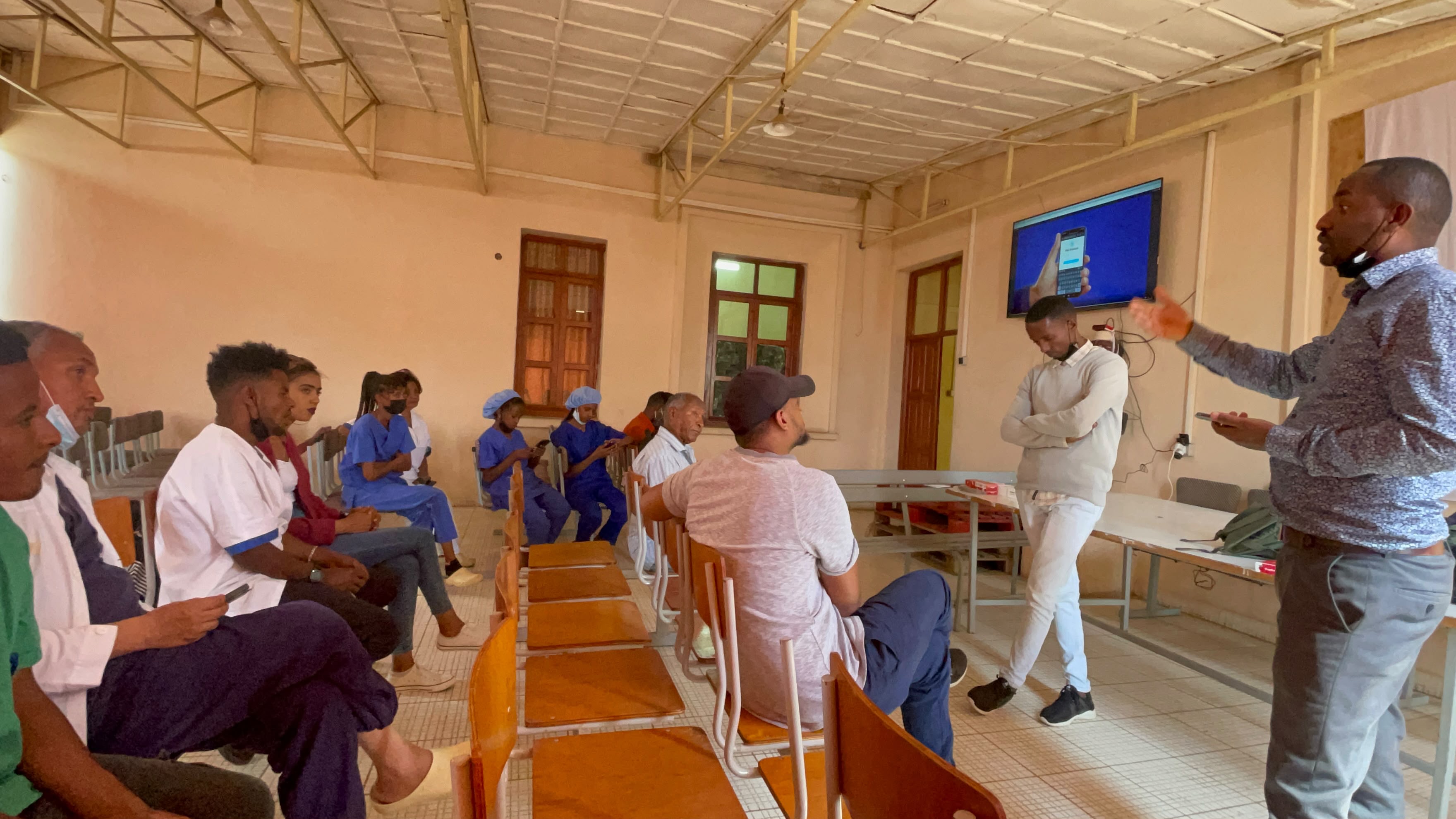 Facilitator demonstrating a public health mobile application on screen to seated health staff