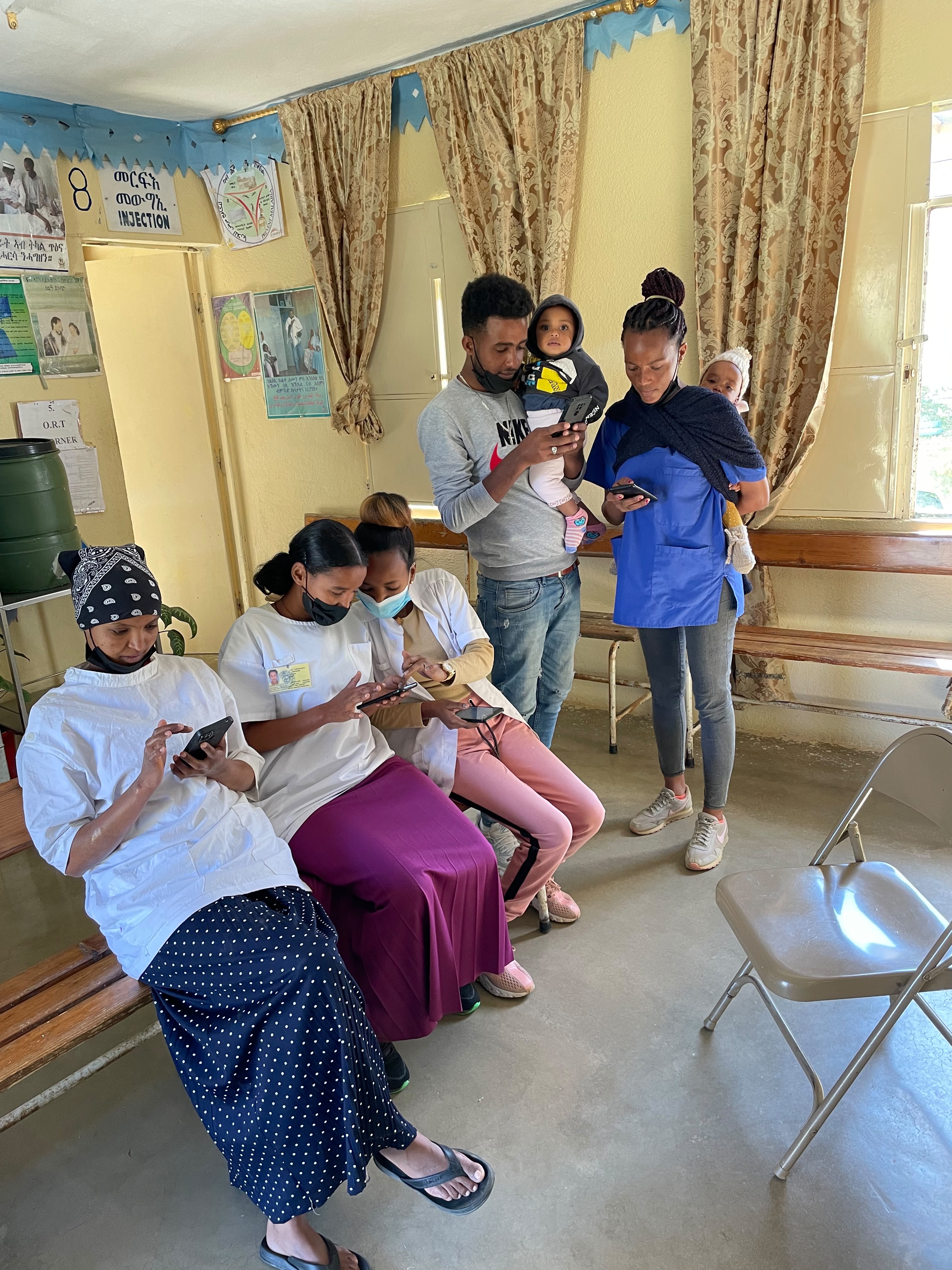 Health workers and parents with young children reviewing mobile health guidance at a clinic