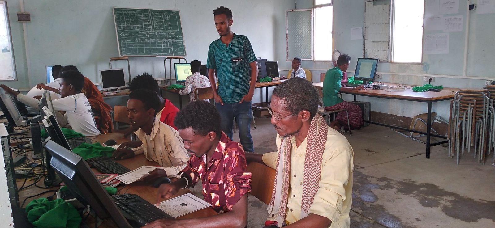 Students learning basic computer applications on desktop machines with an instructor in an ICT lab